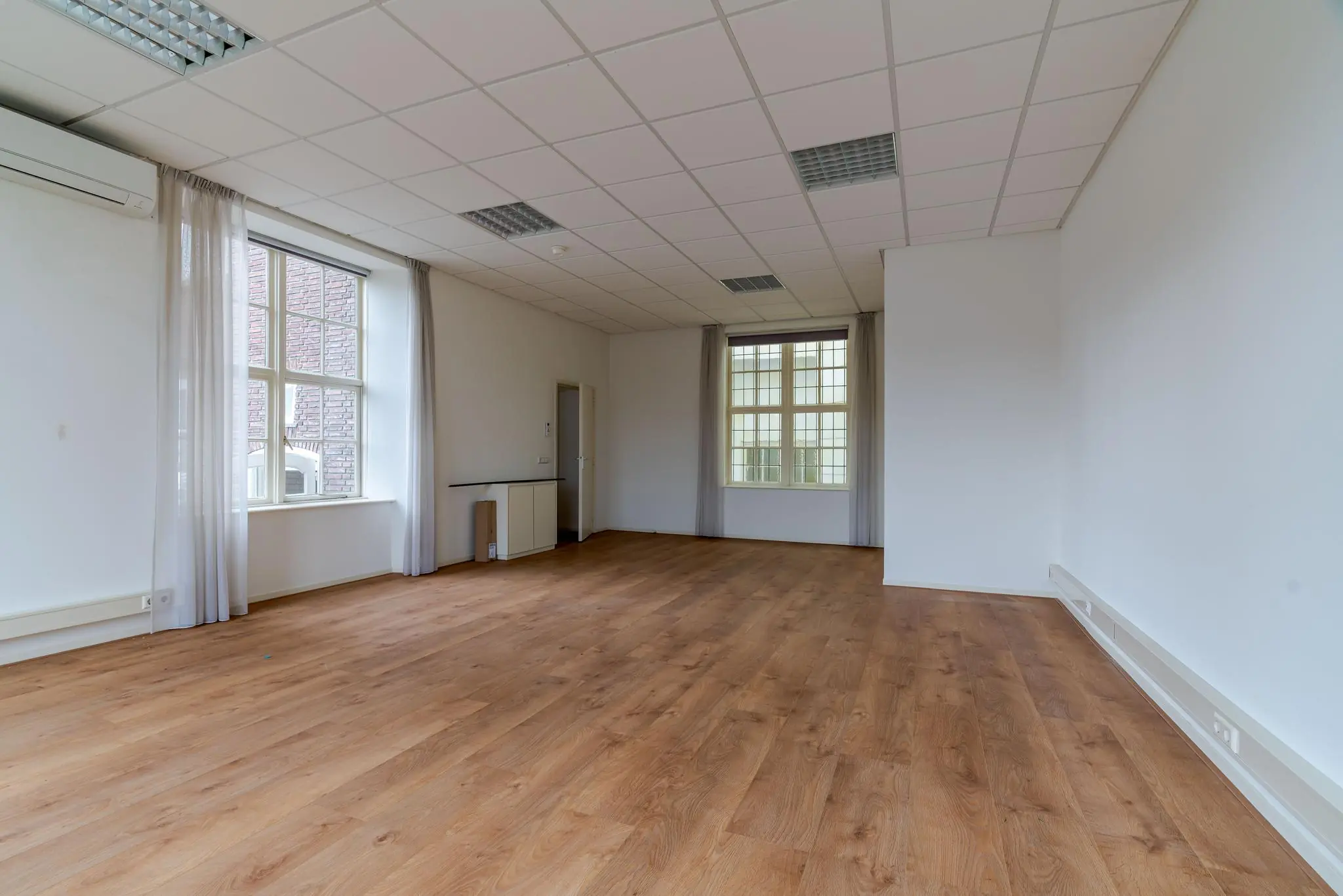 Lichte, lege kantoorruimte met houten vloer aan het Lange Voorhout.